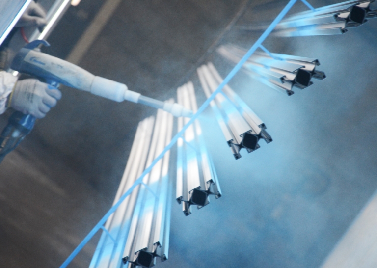 Side angle of a Keystone Koating employee spraying blue powder on product