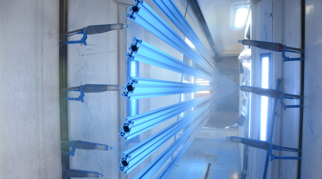 Side angle of a Keystone Koating employee monitoring machine spraying powder on product