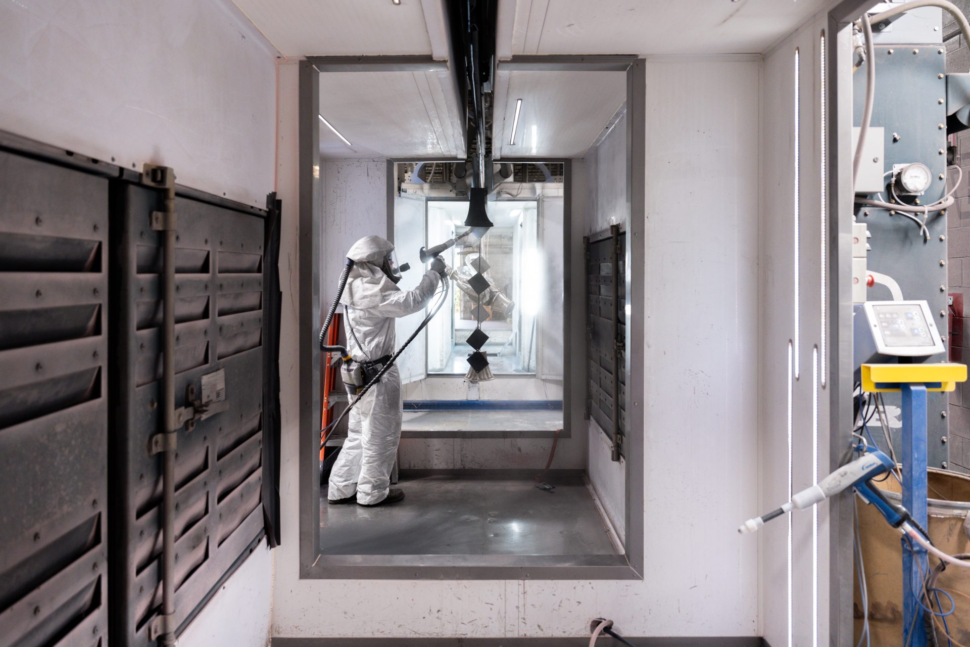 Standing Keystone Koating employee heavily equipped to spray powder on product