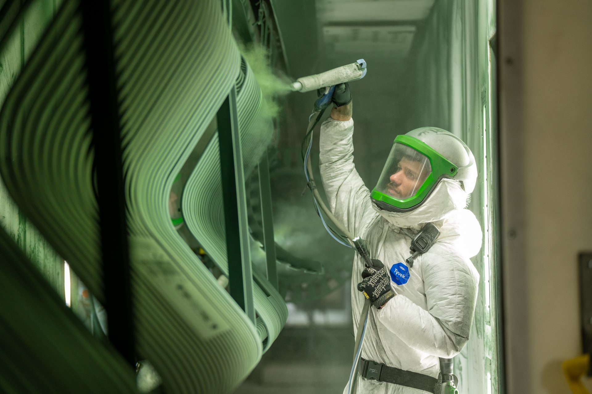 Side angle of Keystone Koating employee equipped to spray green powder on large product